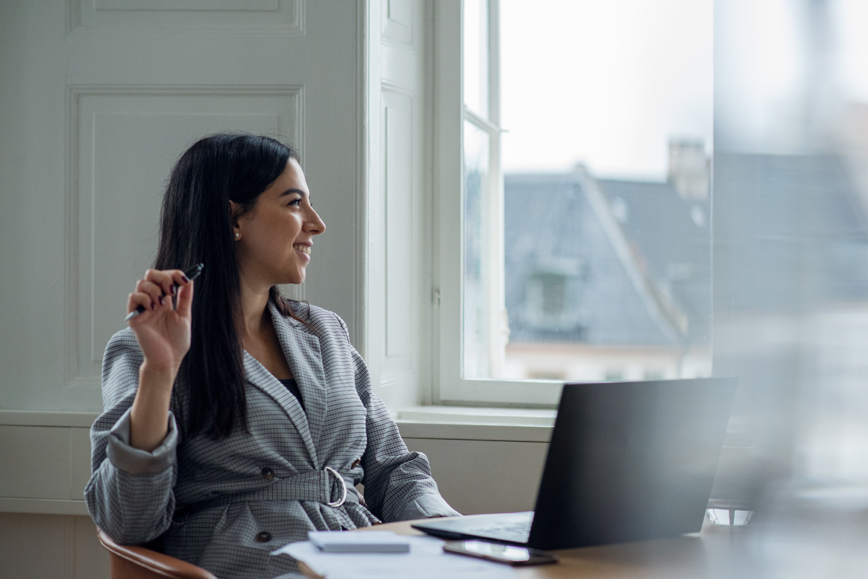 Smilende kvinde på arbejde foran laptop