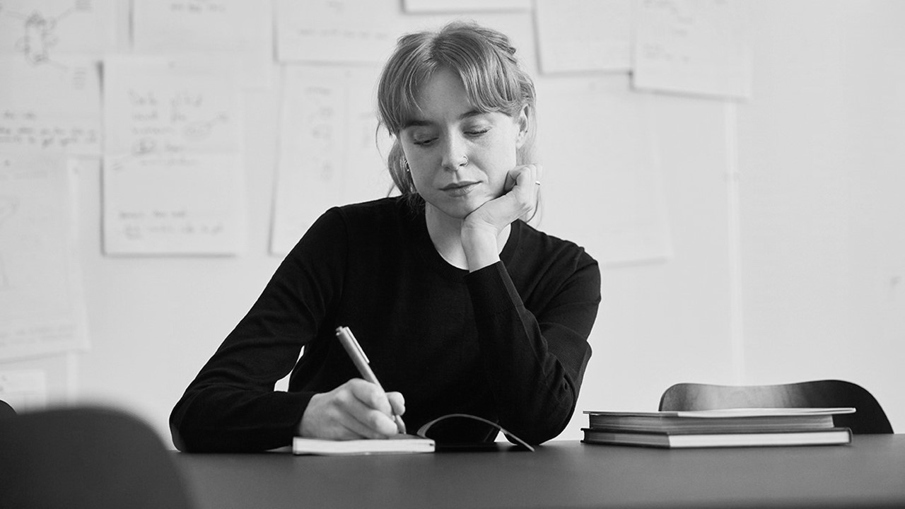 Kvinde skriver i en notesbog, sort/hvid