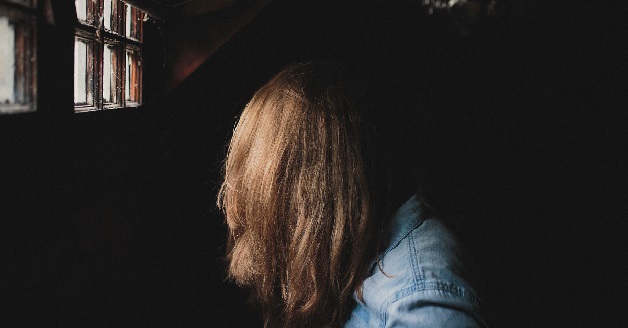 Trist pige står i mørkt rum