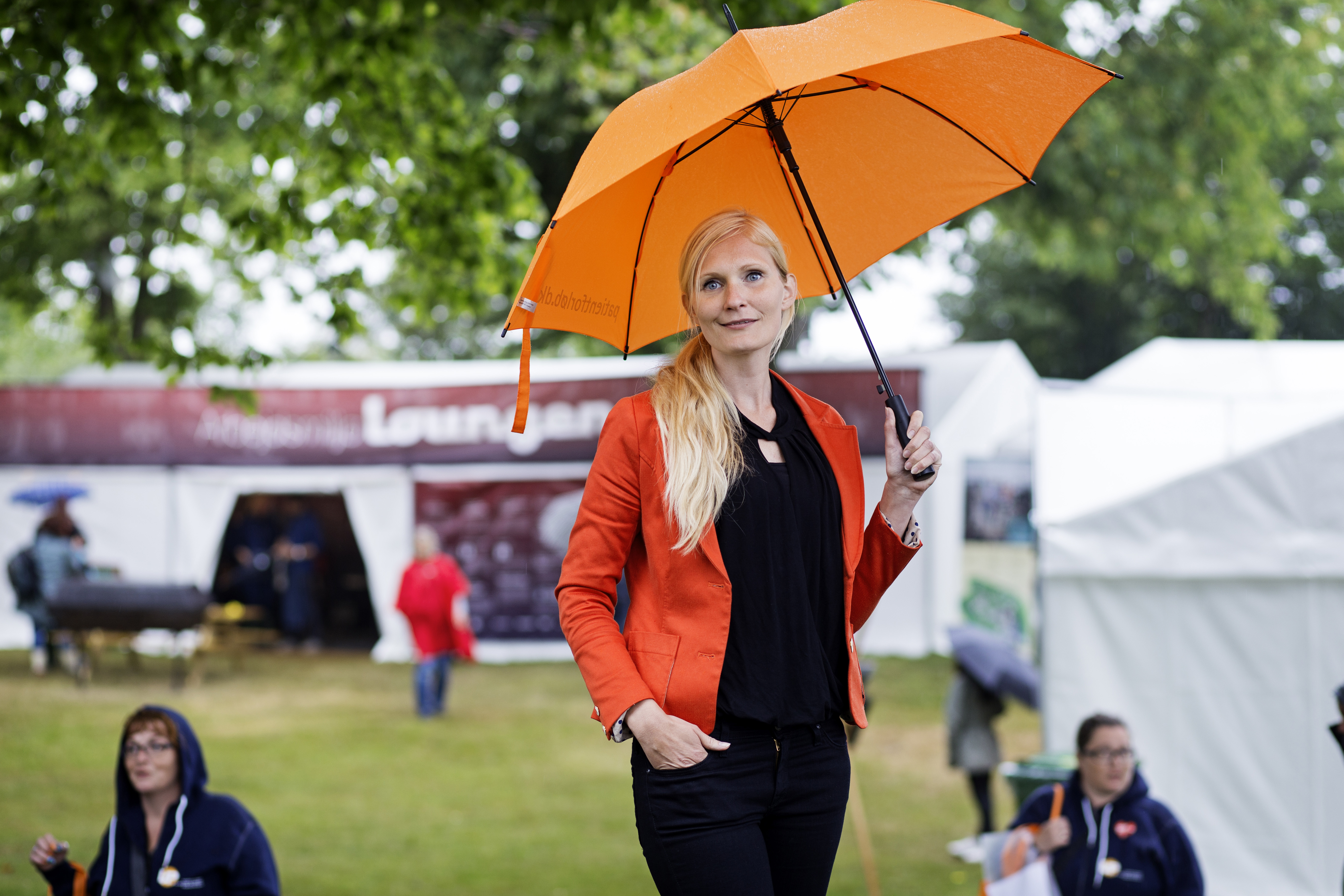 Kvinde står med orange paraply